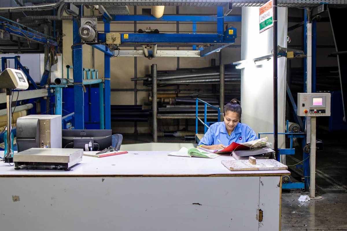 Factory worker in an Indian textile unit checking documents at her desk