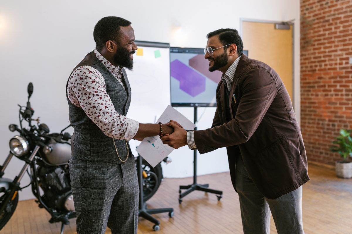 Two colleagues shaking hands in front of a presentation screen