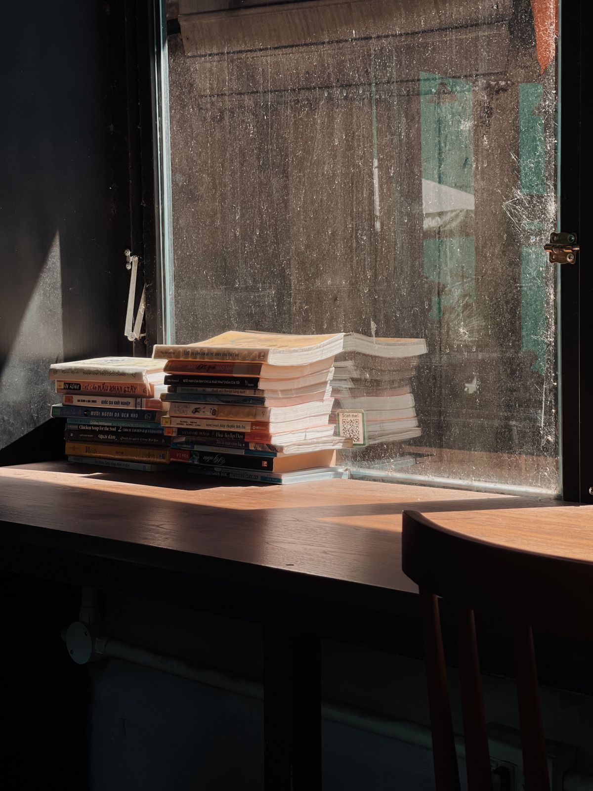 Stack of books on a table beside a window