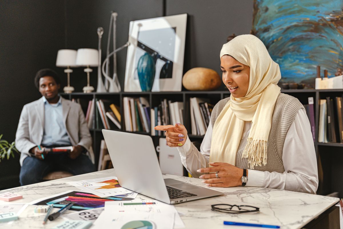 Woman presenting on a laptop to a colleague in a business strategy meeting