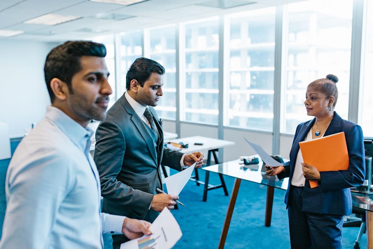 Indian finance team discussing figures in a modern glass office