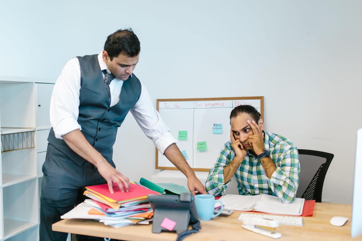 Worried business owner reviewing unpaid bills with a colleague