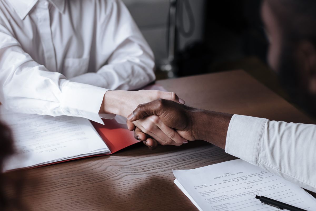 Handshake over contract papers, representing compensation and employment terms