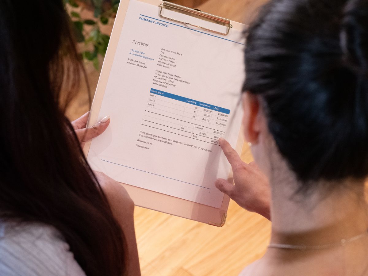 Two people reviewing an invoice on a clipboard