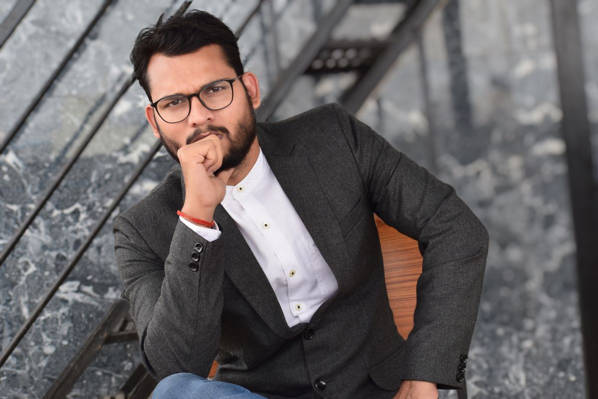 Thoughtful professional in a suit and glasses resting his chin on his hand