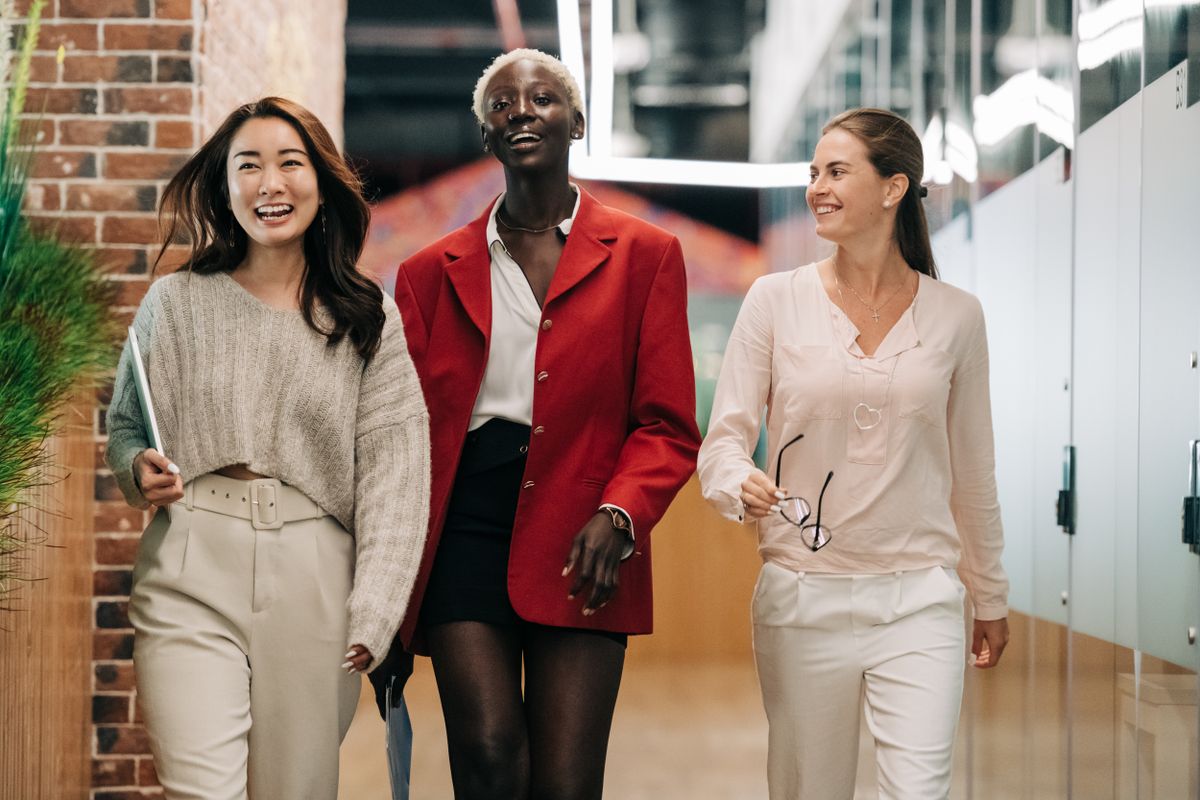 Cheerful businesswomen in elegant clothes walking and smiling in a contemporary office.