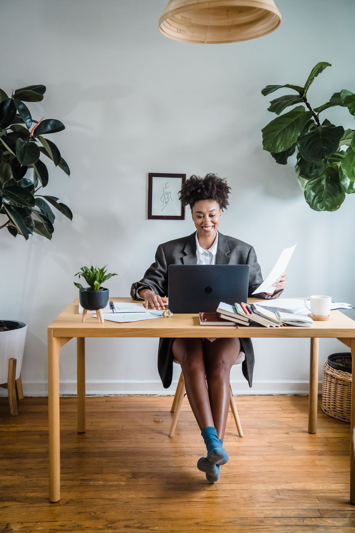 Smiling employee working at a laptop at her desk surrounded by plants