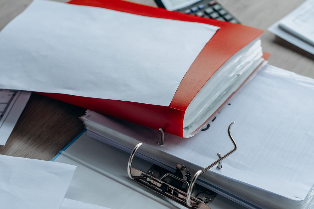 Tidy office desk with binders, papers, and stationery.