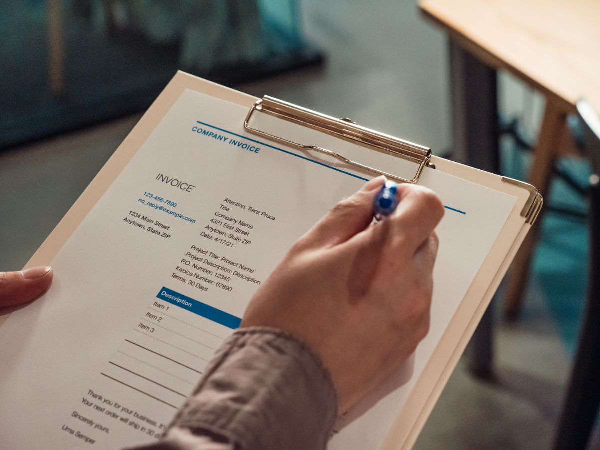 Hand filling in a payroll checklist on a clipboard