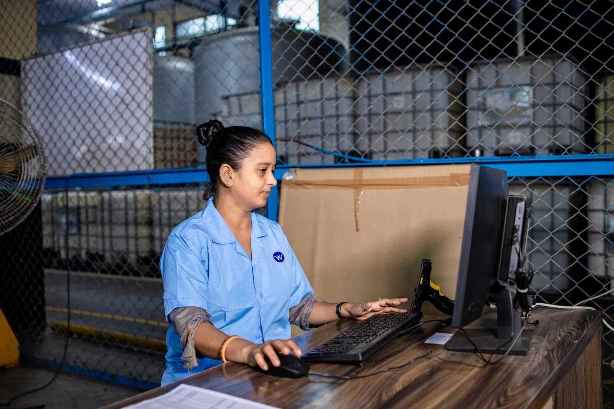 Indian warehouse worker reviewing supplier invoices on a computer