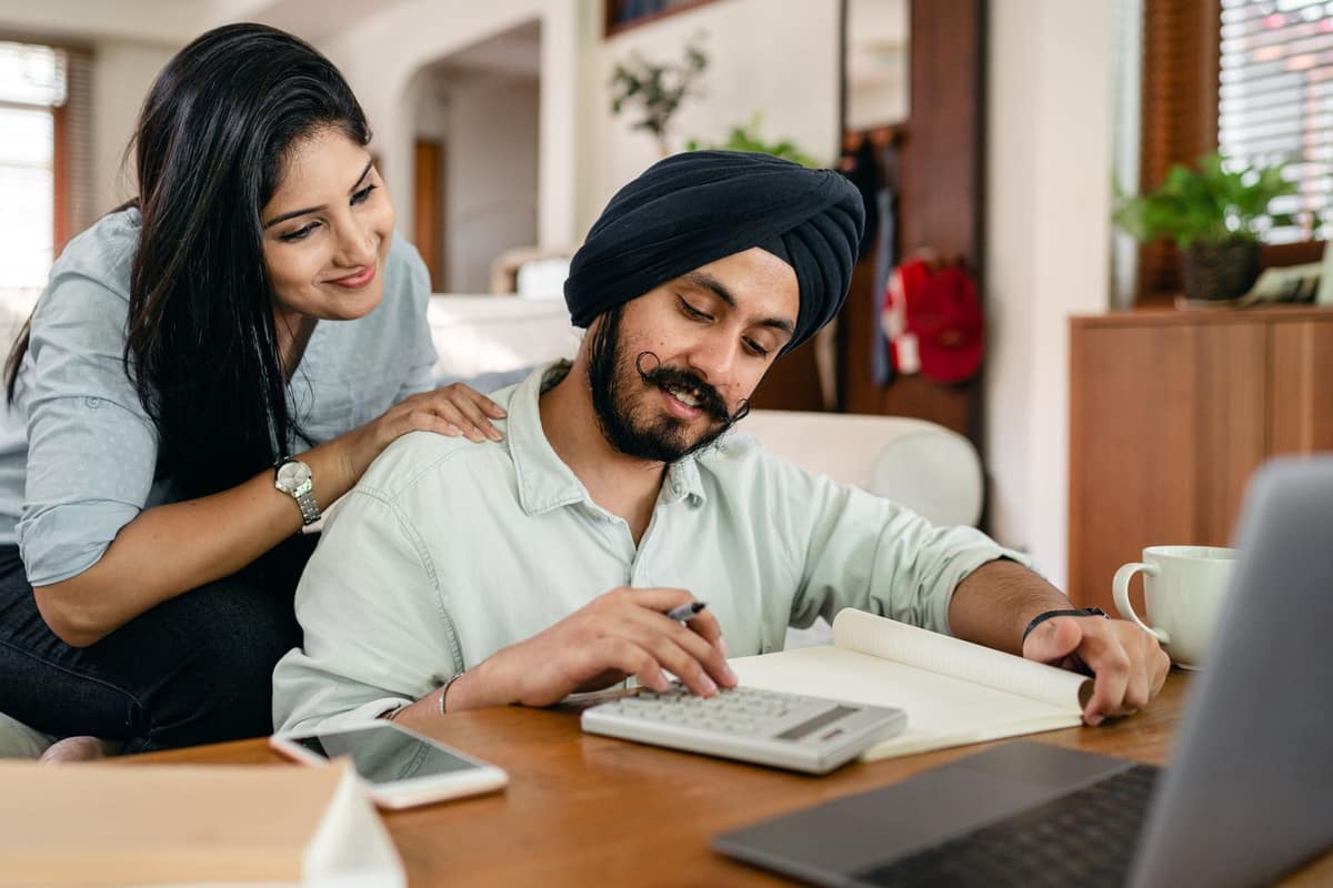 Indian business owner and his accountant reviewing figures with a calculator