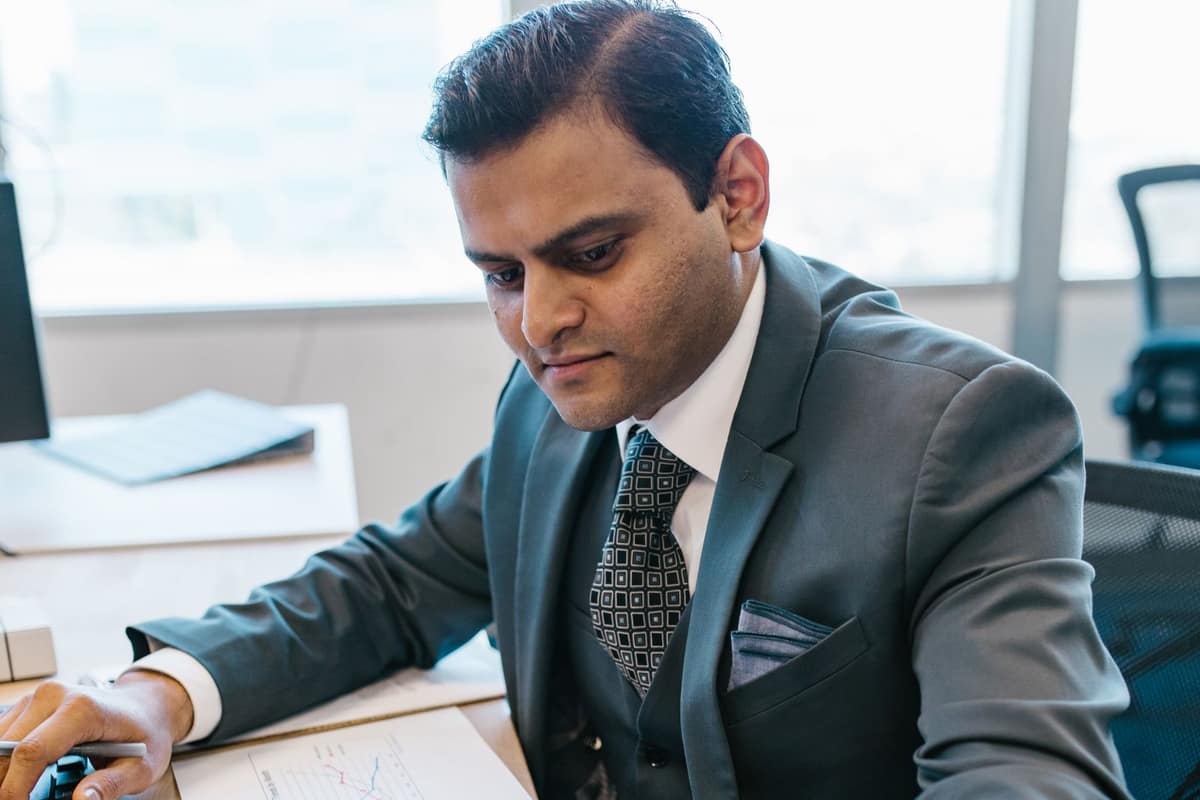 Indian business owner in a suit working through pending filings at his office desk