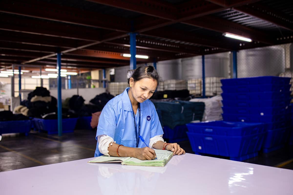 Factory worker in an Indian warehouse writing up dispatch records