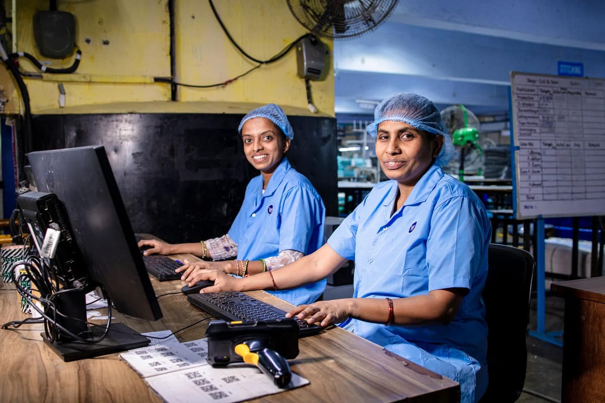 Two women at computers in an Indian factory office, working through the year’s figures