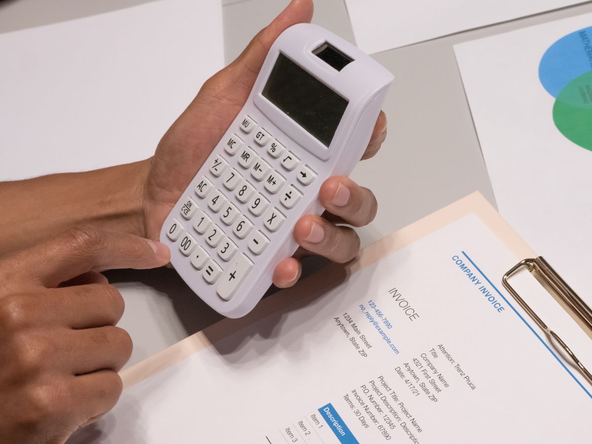 Hands using a calculator next to a company invoice for GST returns