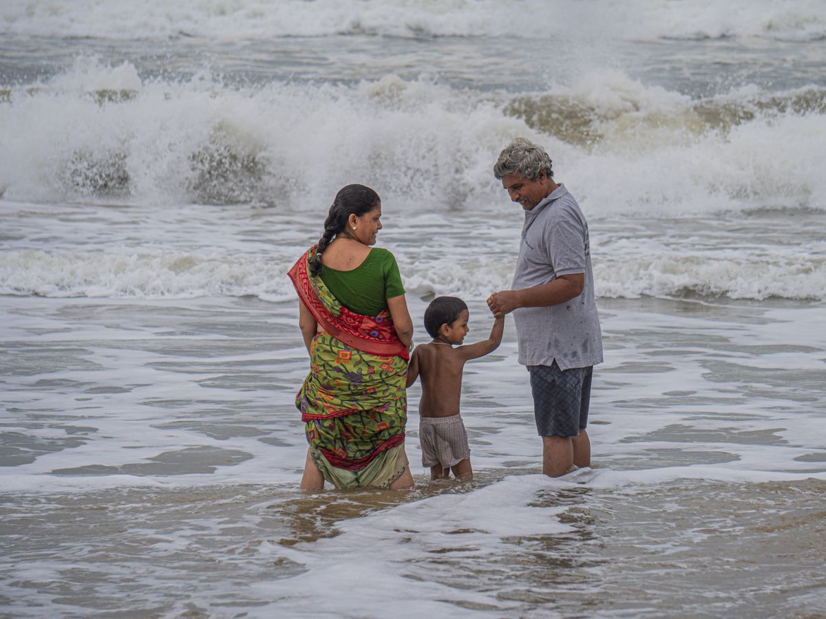 Indian family wading in the sea on a holiday, representing employee leave