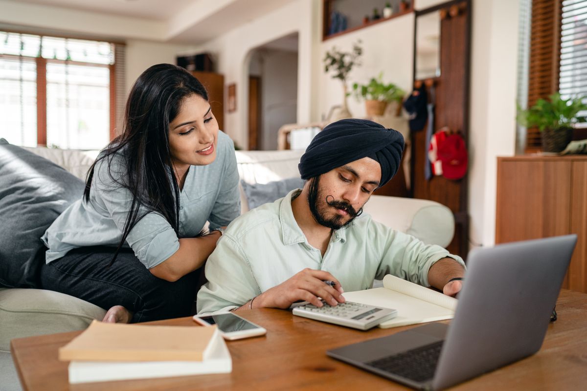 Man calculating salaries with a calculator and notebook while running payroll in India