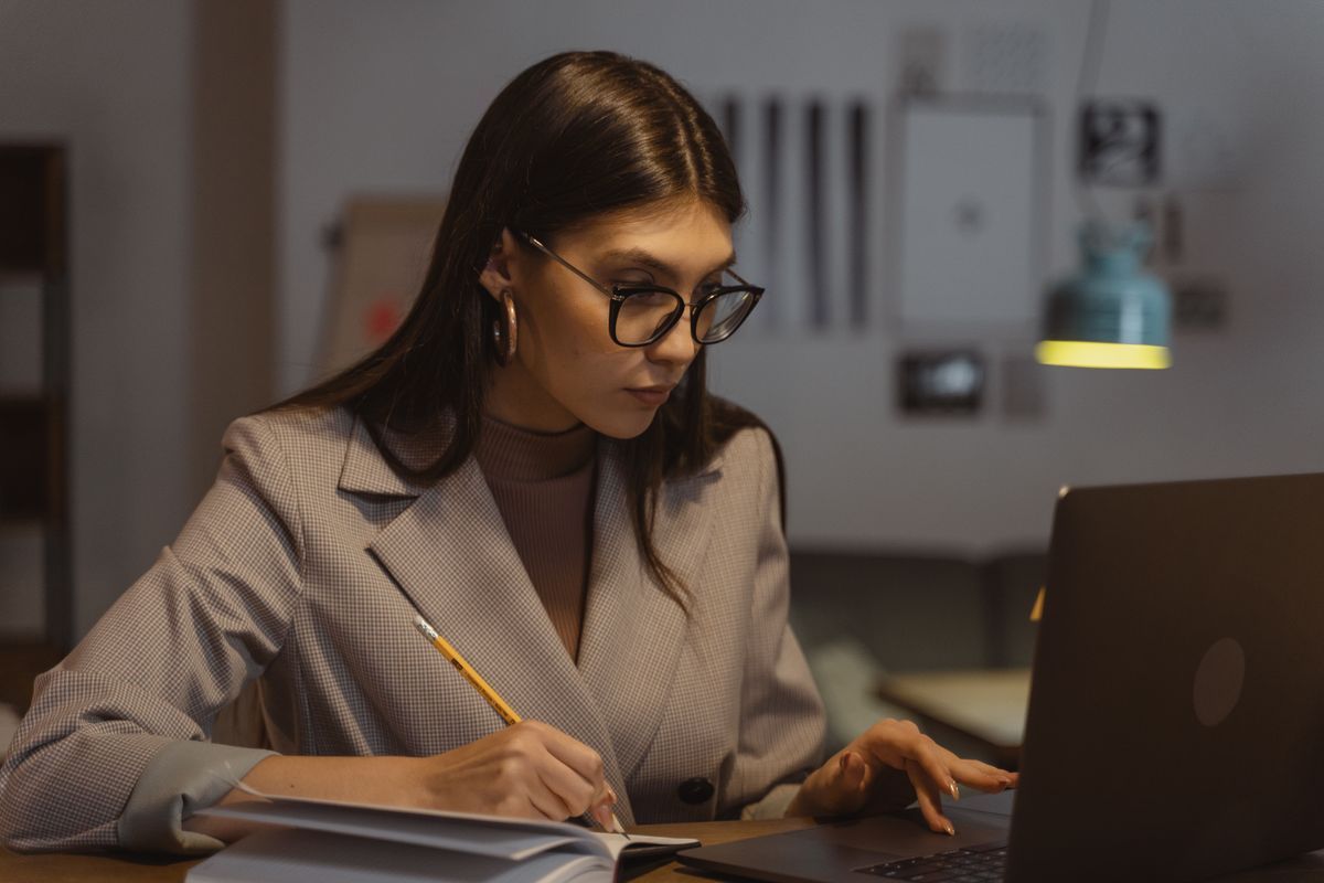 Confident businesswoman working on a laptop and taking notes in an office.