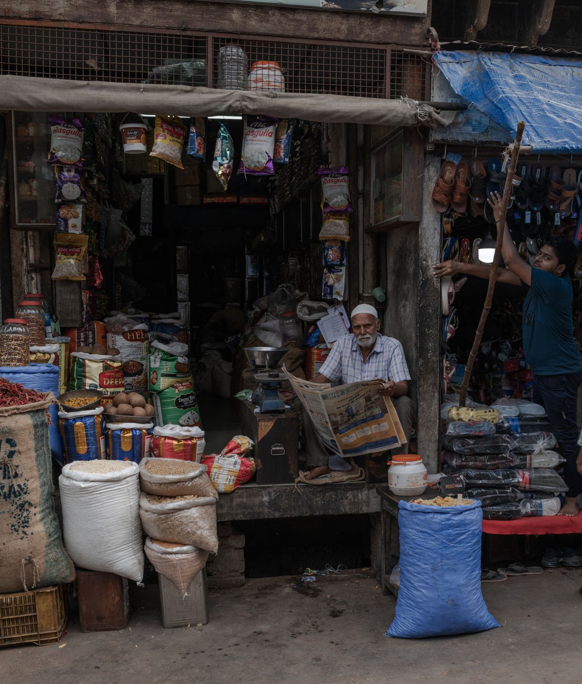 Shopkeepers in a busy Indian market shop stocked with goods