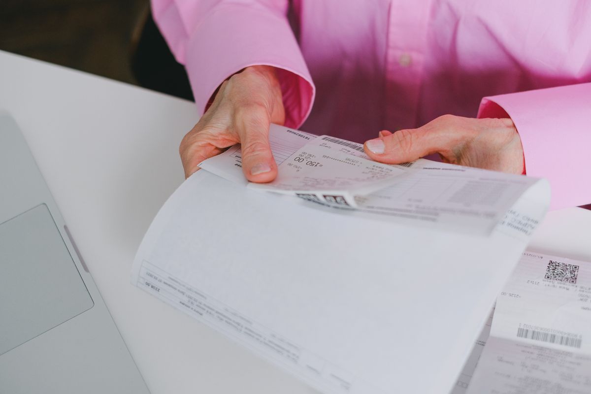 Hands holding a purchase bill and receipt to claim input tax credit