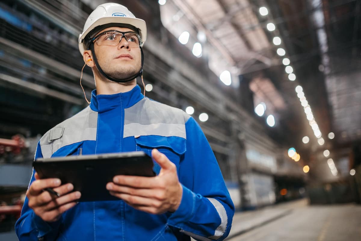 Engineer with a tablet checking production in a large factory