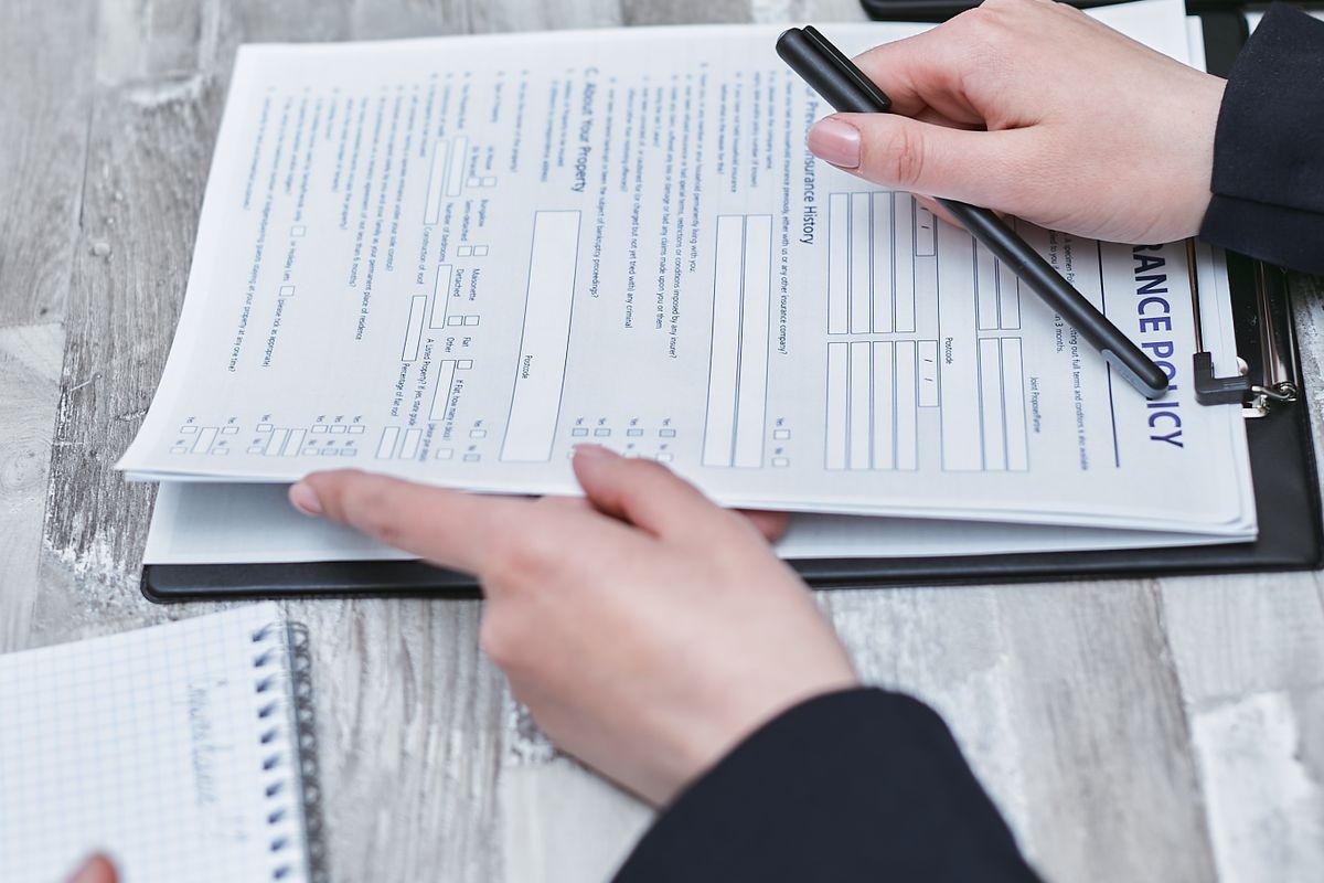 Close-up of hands analyzing policy paperwork with a pen on a table.