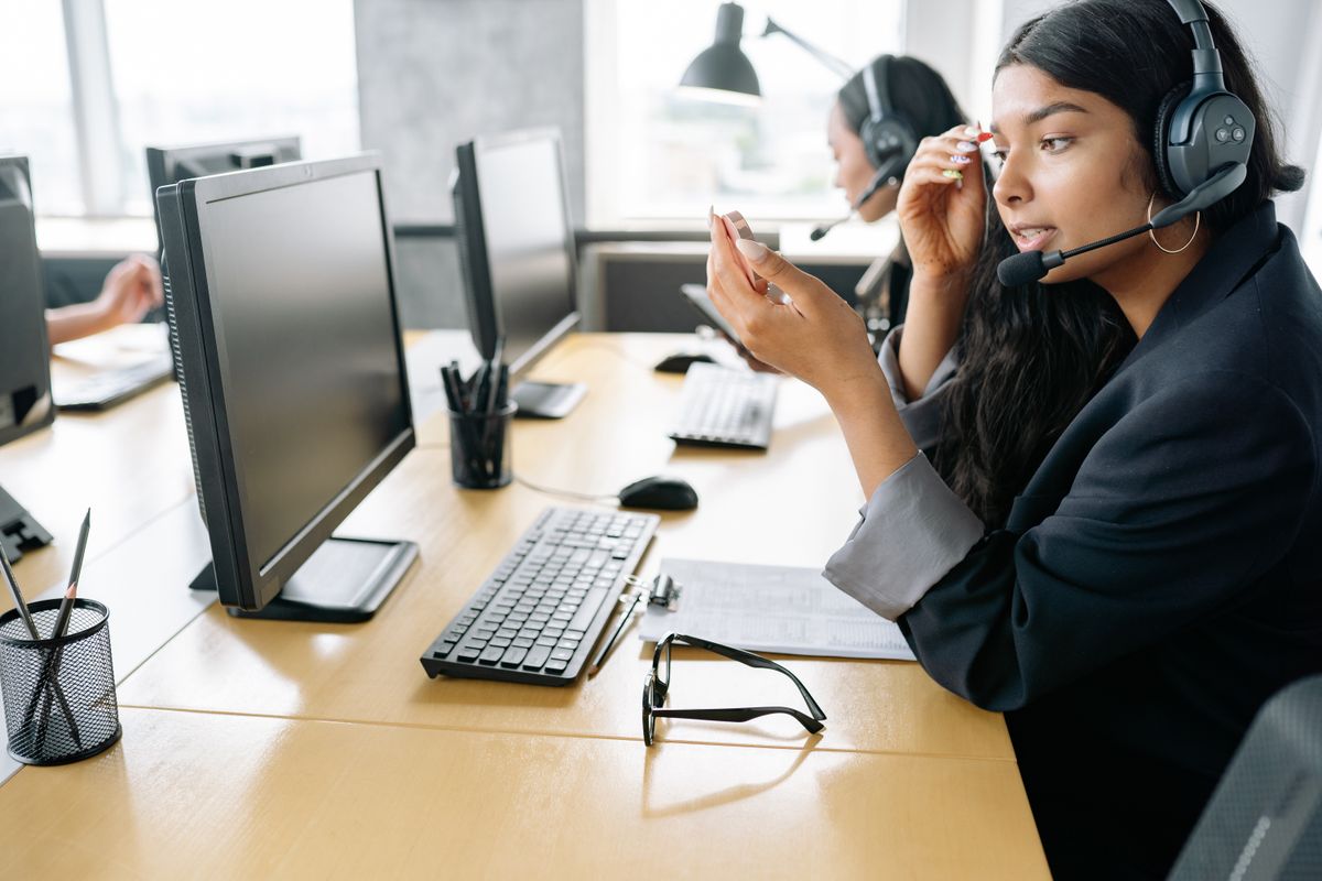 Sales representative on a headset call at a busy desk