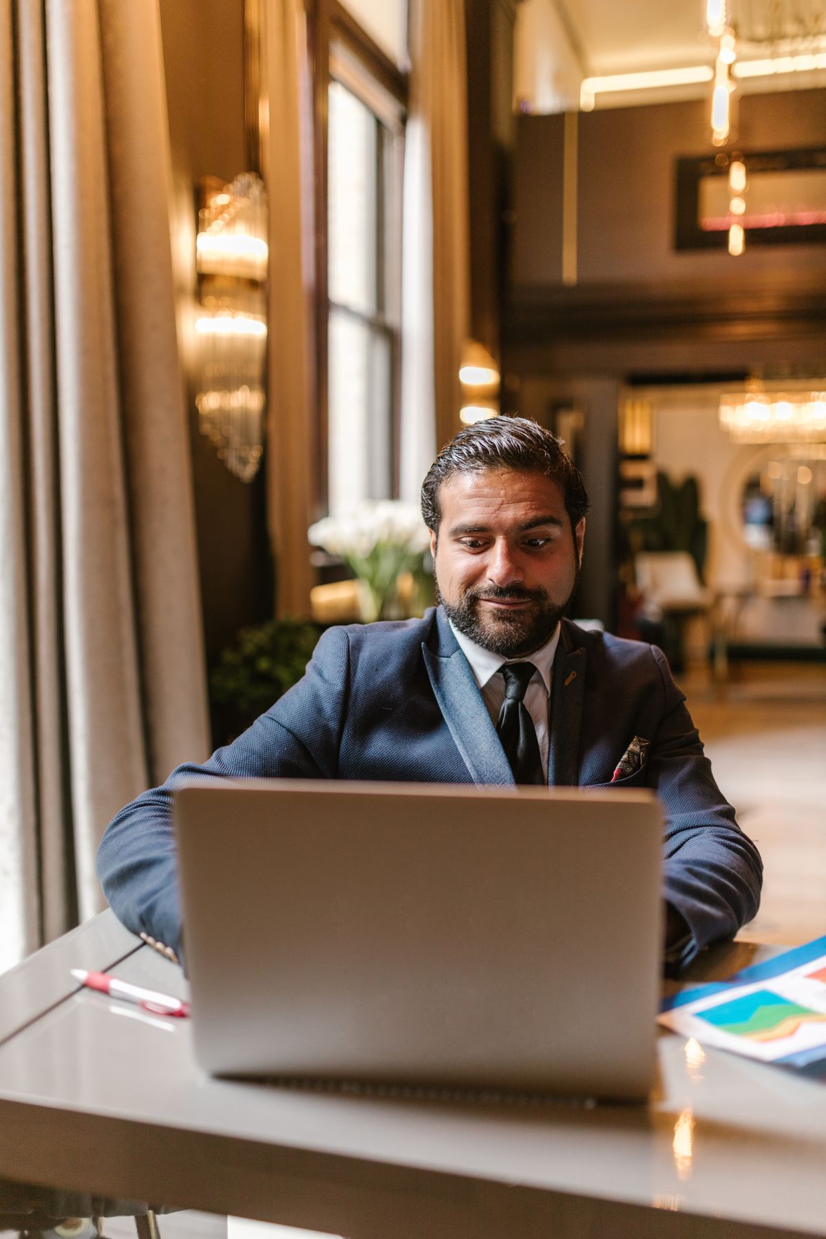 Business leader in a suit working on a laptop in a lounge