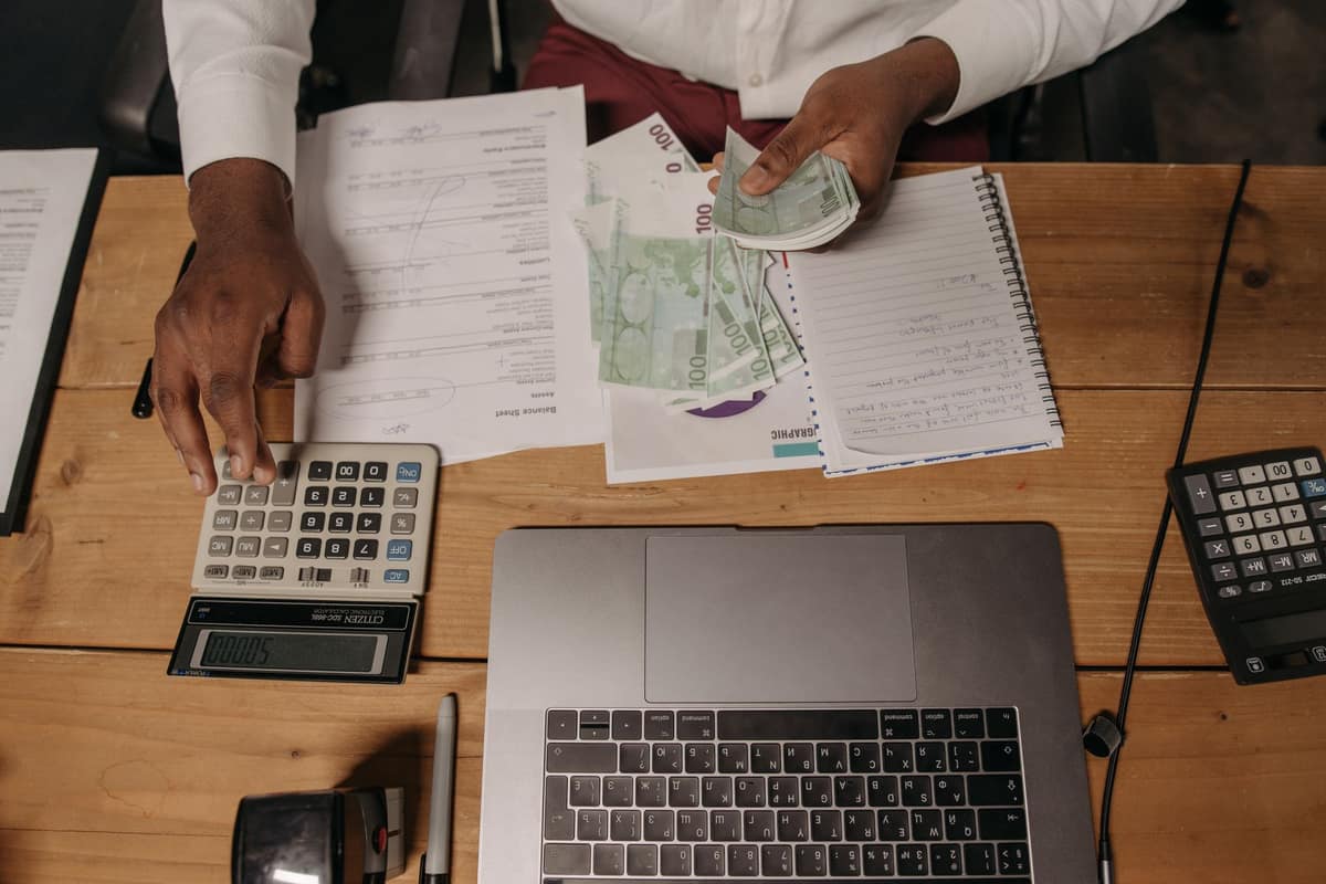 Business owner matching payments against invoices with a calculator and laptop