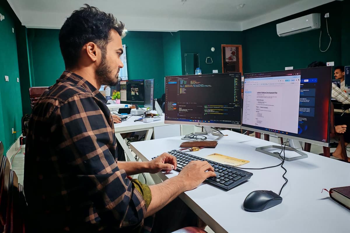 Software developer working at a dual-monitor desk in an Indian office