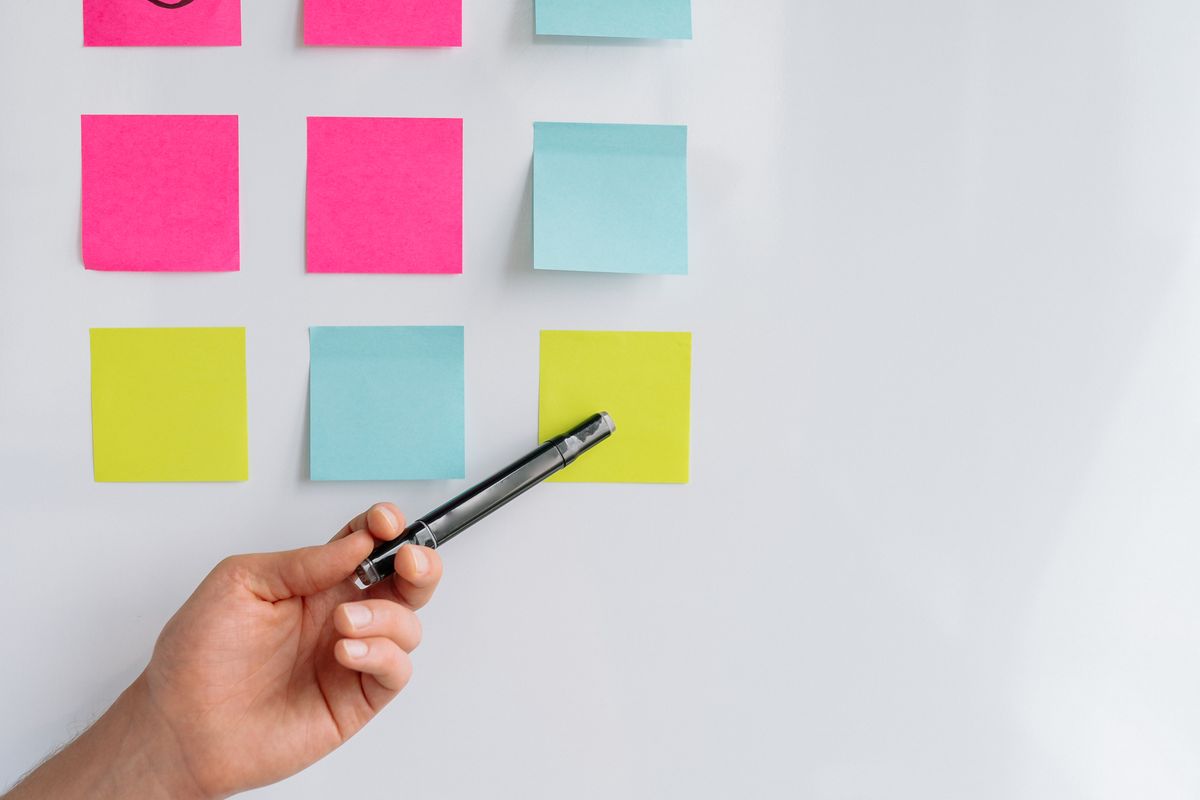Hand pointing to sticky notes on a whiteboard for brainstorming sessions.