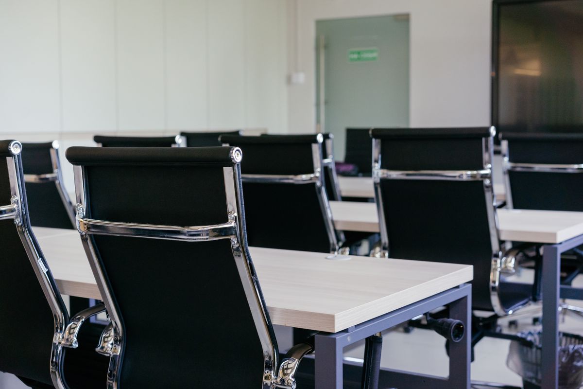 Modern conference room with black chairs and white desks, empty before a meeting.