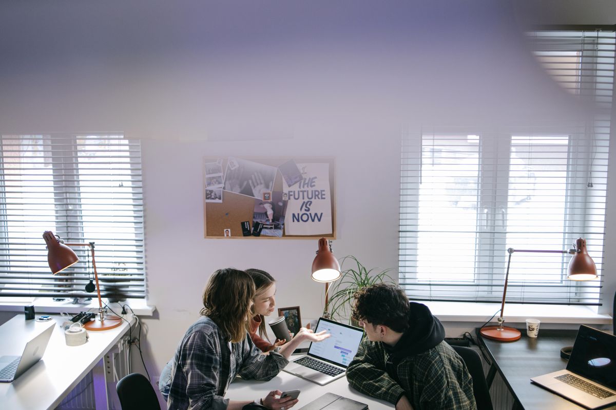 A group of people discussing ideas around laptops in a bright, modern office space.
