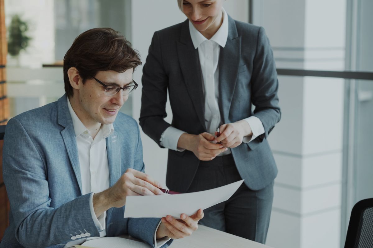 Two business professionals discussing a document in a modern office setting.