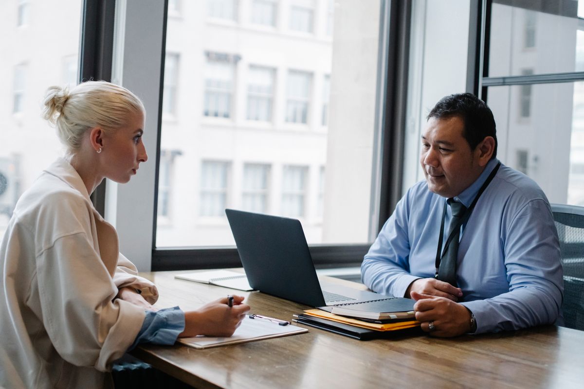 Manager and employee discussing performance across a table with a laptop
