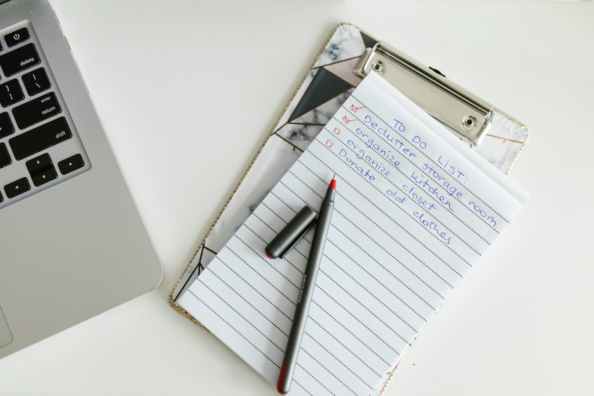 A neatly organized to-do list on a clipboard next to a laptop and pen.