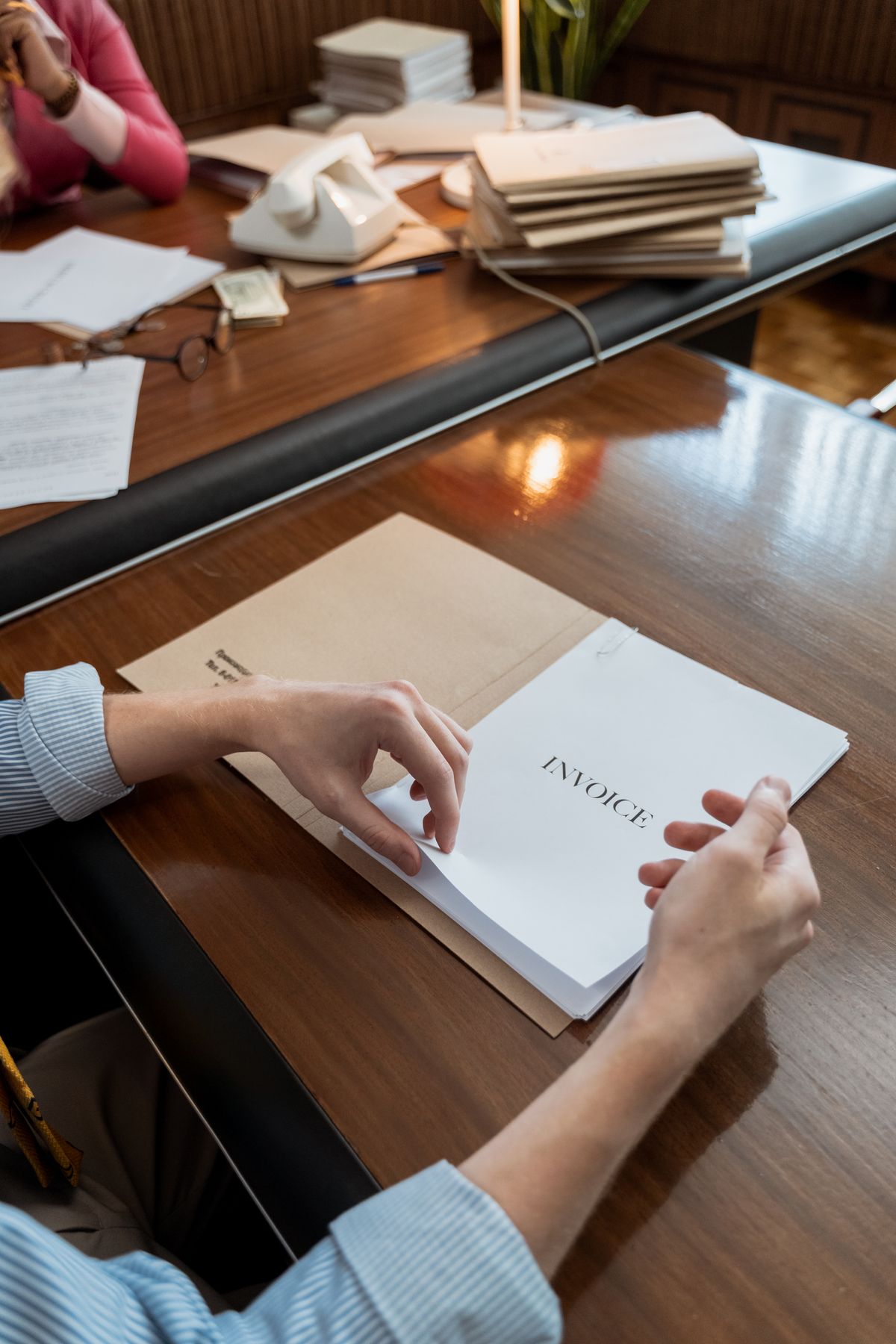 Hands holding an invoice on a desk