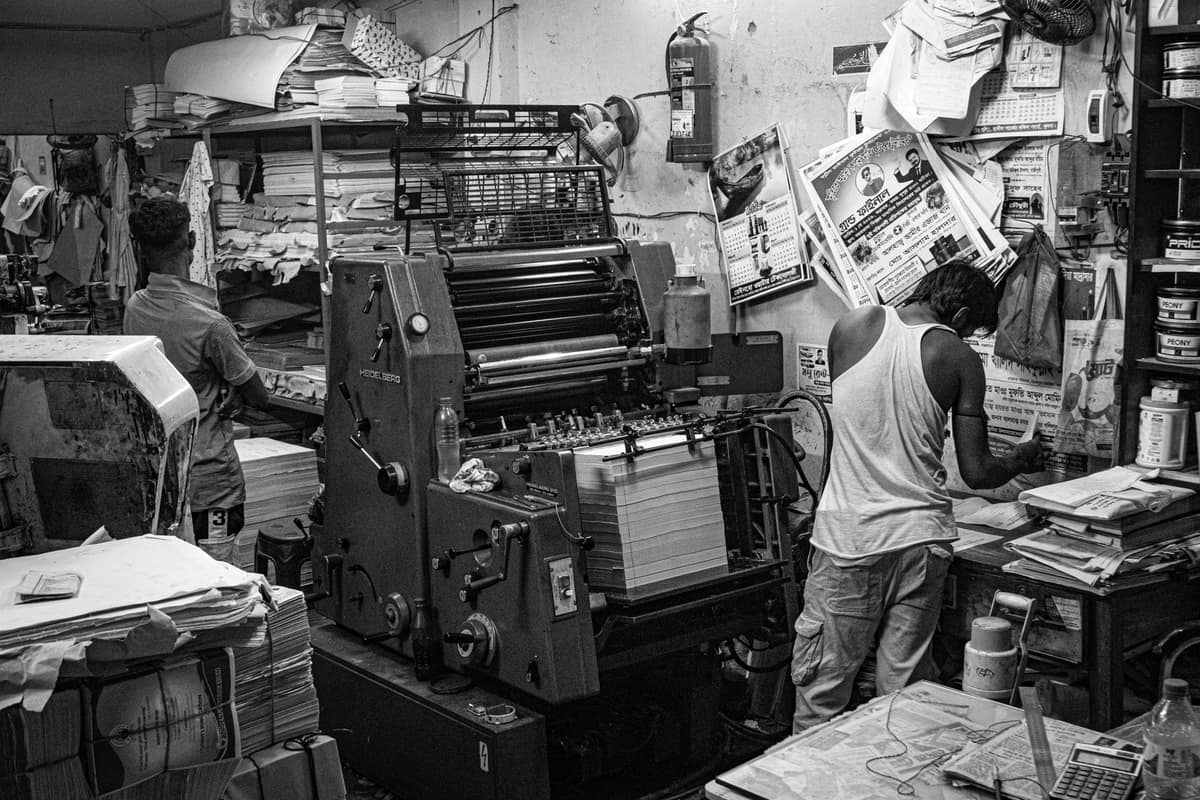 Workers running printing machines in a busy Indian print shop