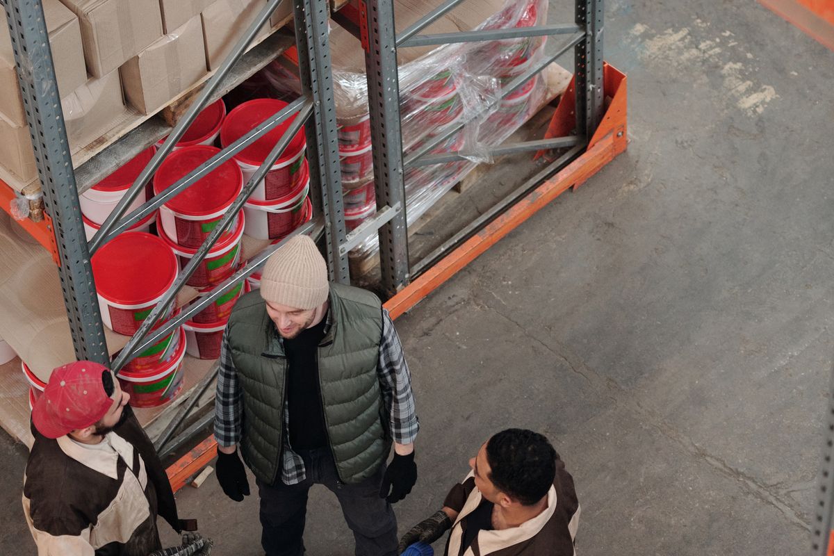 High-angle view of a team discussing logistics in an industrial warehouse.
