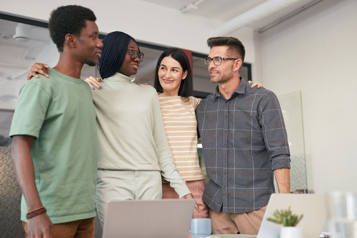 Four diverse colleagues sharing a moment of teamwork and collaboration in an office.