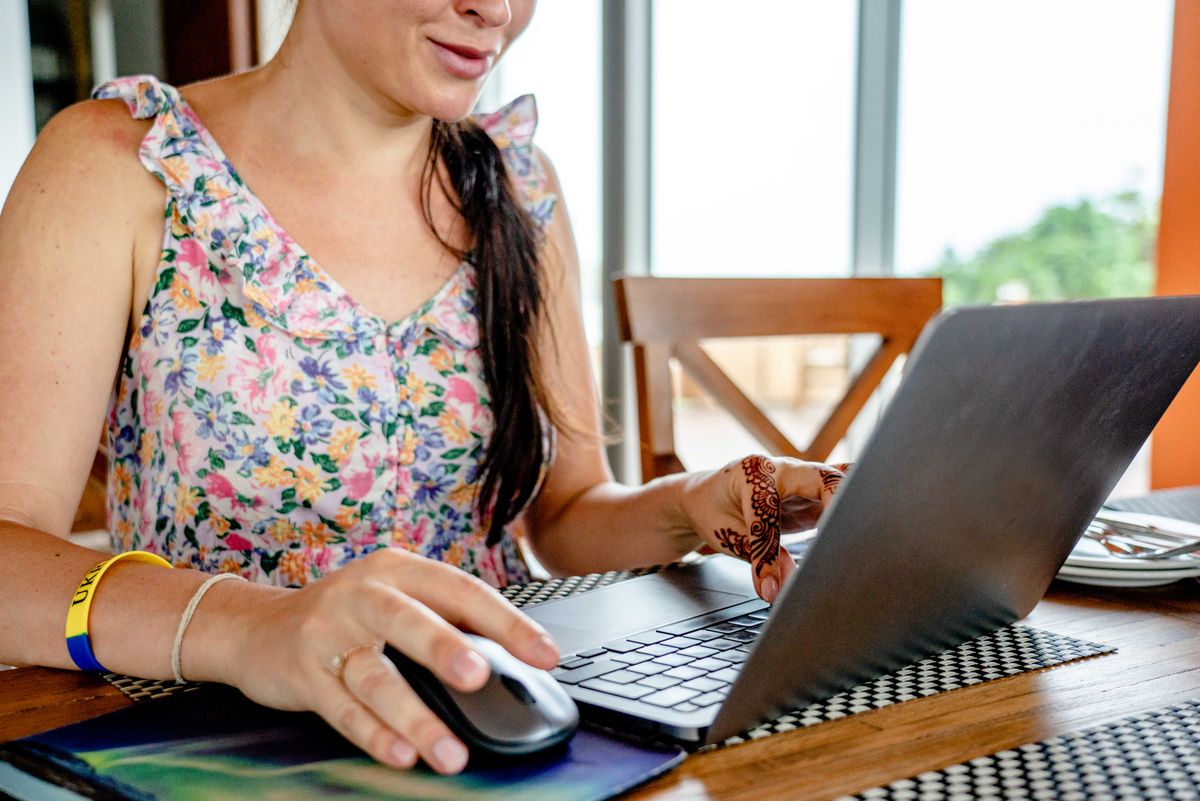 Woman working on a laptop at a table, reviewing an HR self-service interface