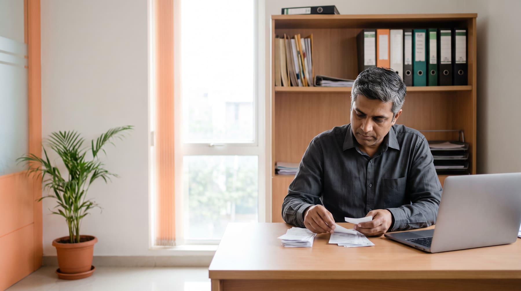 A chartered accountant sorting purchase bills beside a laptop