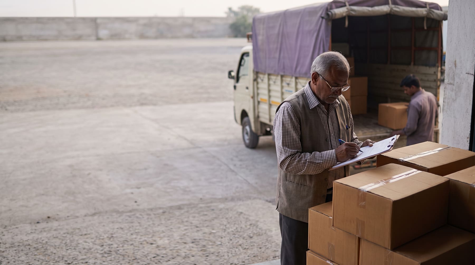 A storekeeper checking a delivery of cartons against a purchase order