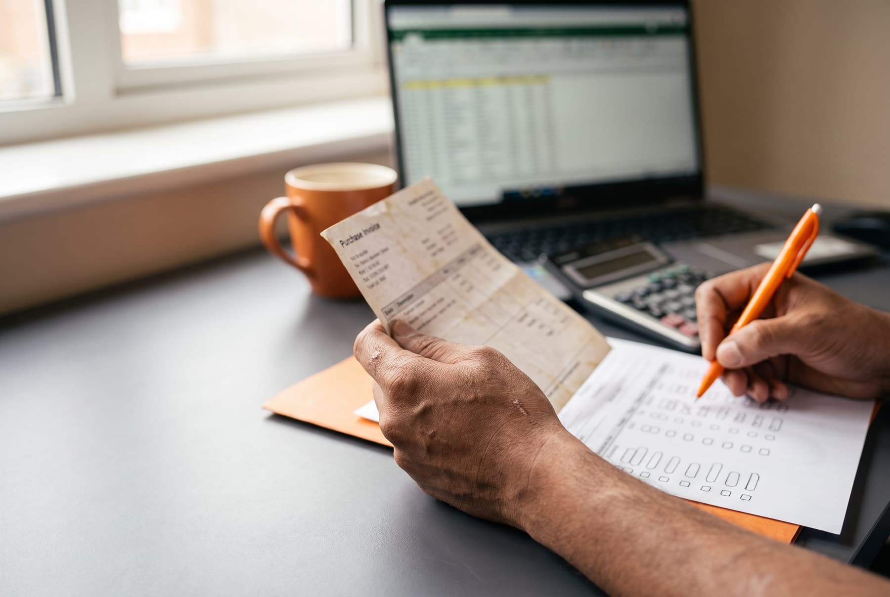 An accountant marking a matched invoice on a printed reconciliation sheet