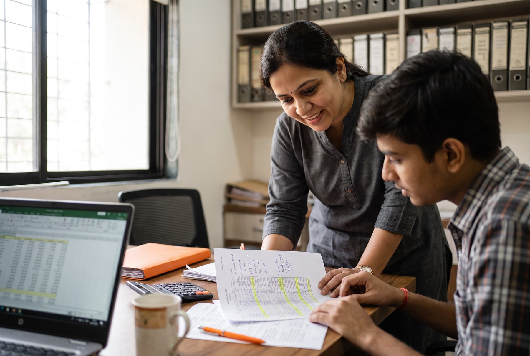 A chartered accountant and her assistant reviewing year-end GST working papers at a desk